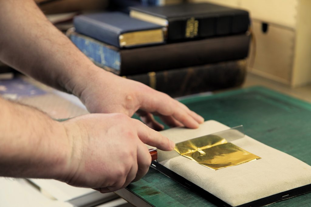 cutting gold leaf on a gilding cushion