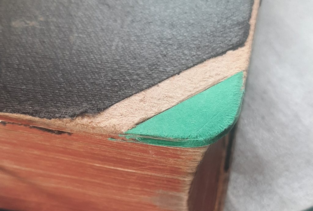 Corner of hardback book rebuilt with card