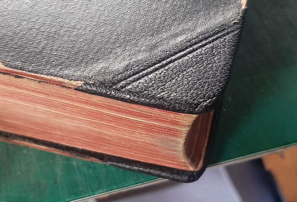 Corner of hardback book recovered in leather with blind tooling